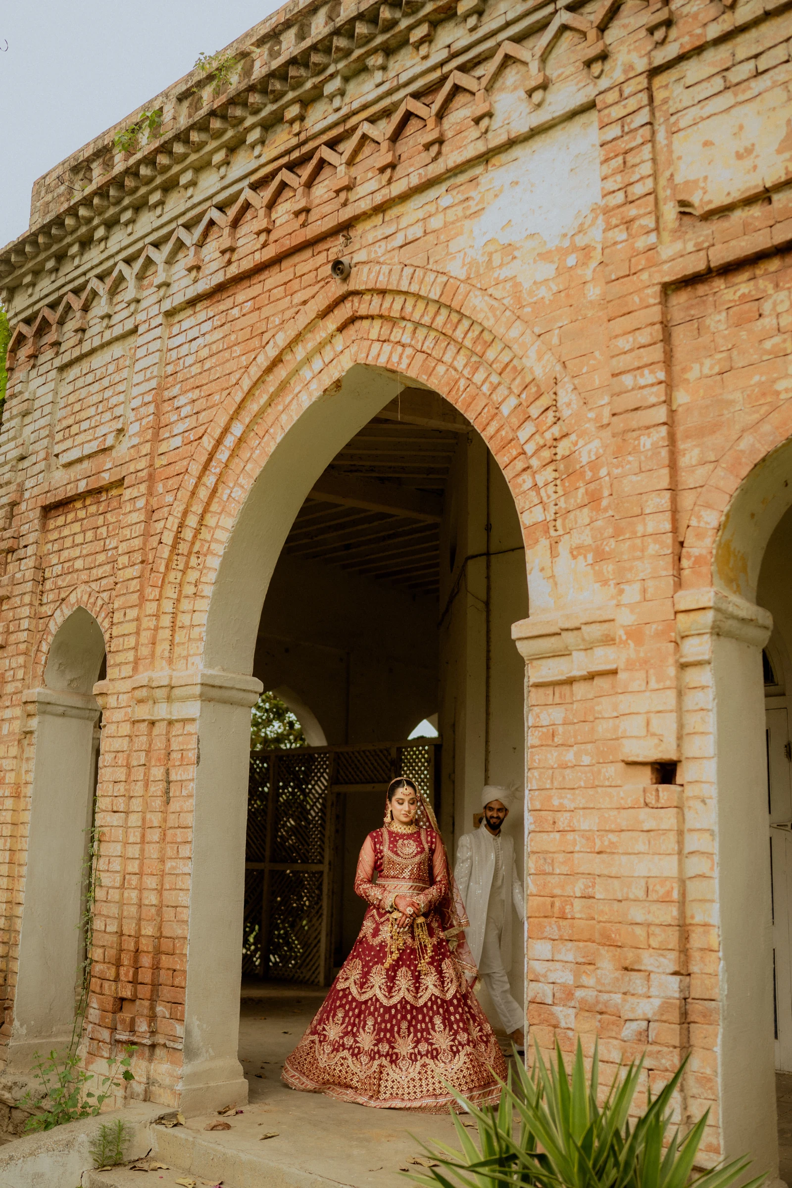 A bride and groom beneath an ornate brick arch