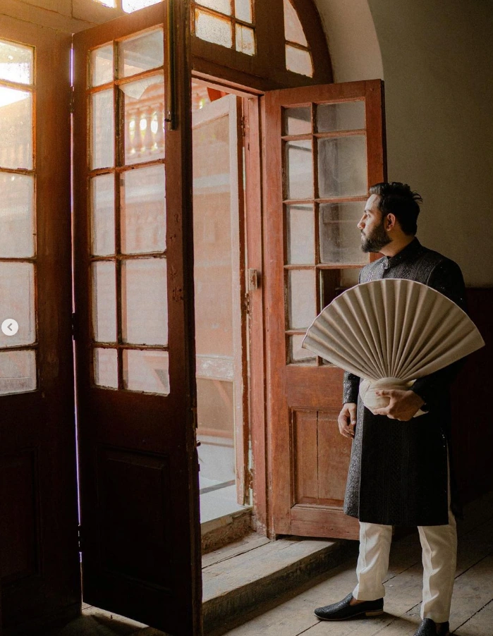 Groom beside a sunlit wooden window